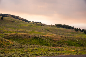 Fototapeta premium Dark clouds hover over mountain hills at sunset