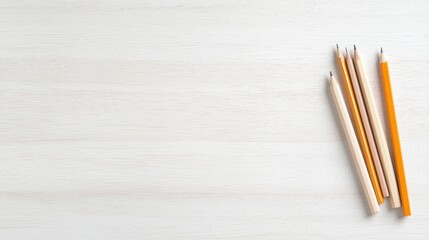 Obraz premium Wooden pencils lie on a bright white wooden desk surface with ample copy space.