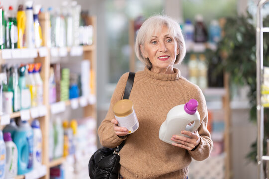 Concerned female customer trying to make choice between liquid laundry soaps in supermarket
