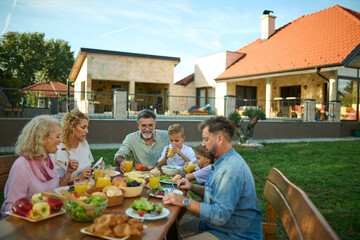 Happy family enjoying weekend brunch together in backyard