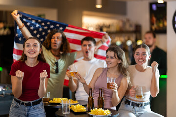 Group of friends fans watching match cheering with US flag in bar