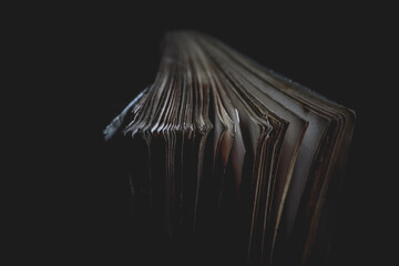 open book on black background, Close-Up of Aged Book Pages in Soft Lighting