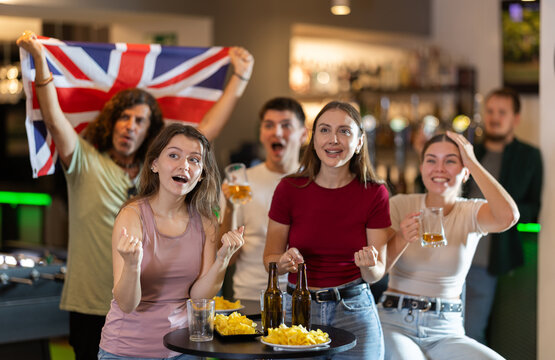 Emotional United Kingdom fans with the national flag watch the match on TV with interest and actively comment - Powered by Adobe