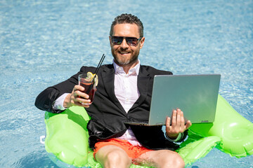 Successful business man in suit in pool water. Business man in suit working on laptop in swimming pool. Travel tourism and business concept. Crazy male office business employee using laptop.