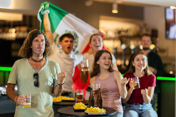 Group of friends cheer together for their favorite Mexican team in a beer bar