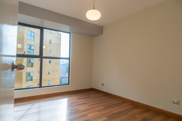 habitacion de departamentomoderno con ventana y  paredes blanca, piso de melamina