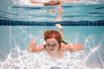 Underwater child swims in pool, healthy child swimming and having fun under water.