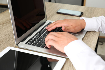 Businessman using laptop at wooden table, closeup. Modern technology