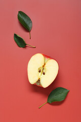 Half of apple and leaves on red background, flat lay