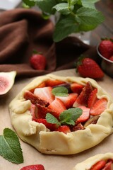 Uncooked galette with strawberries, figs and mint on table, closeup