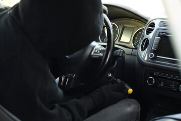 Thief trying to start ignition switch with screwdriver, closeup. Car hijacking
