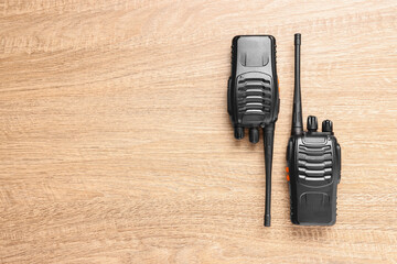Walkie talkies on wooden table, top view. Space for text