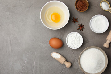 Baking powder and other products on grey textured table, flat lay. Space for text