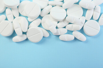 Many antibiotic pills on light blue background, top view. Space for text