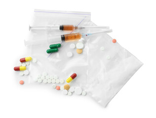 Drug addiction. Different pills, plastic bags with powder and syringes isolated on white, top view