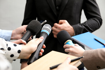 Group of journalists interviewing businessman on grey background, closeup