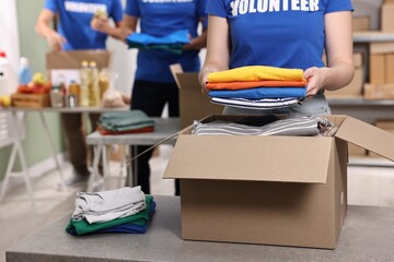 Volunteers packing donation goods at tables indoors, closeup
