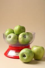 Kitchen scale with apples on beige background
