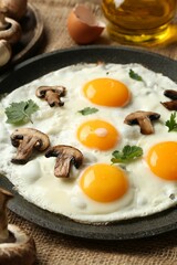 Tasty fried eggs with mushrooms and parsley served on table, closeup