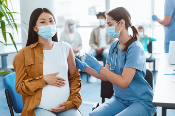 Vaccination In Pregnancy. Pregnant Asian Woman Getting Vaccinated For flu Prevention, Nurse Giving...
