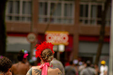 Obraz premium Mulher de costas com tiara com penas vermelha no carnaval de rua de São Paulo. 