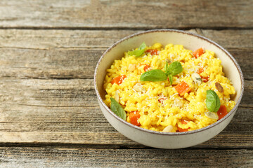 Delicious pumpkin risotto in bowl on wooden table, closeup. Space for text