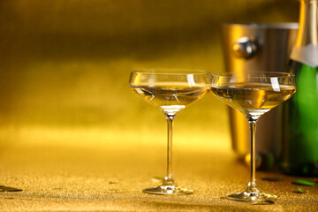 Champagne in glasses, bottle and ice bucket on golden background. Space for text