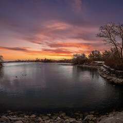 Serene sunset over calm waters, city skyline in the distance.