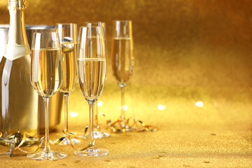 Champagne, bottle, ice bucket and streamers on golden background. Space for text