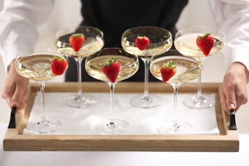 Waiter holding tray with glasses of champagne indoors, closeup