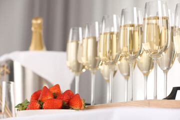Champagne in glasses and strawberries on table indoors, closeup