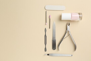 Set of pedicure tools on beige background, flat lay. Space for text