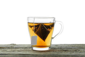 Tea bag in glass cup with hot drink on wooden table against white background