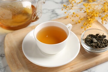 Refreshing green tea and dry leaves on white marble table, closeup