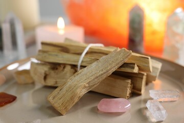 Palo santo sticks, gemstones and burning candle on table, closeup
