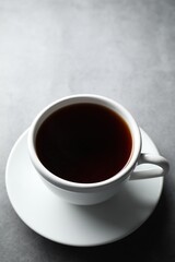 Refreshing black tea in cup on grey table