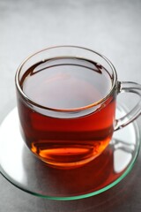Refreshing black tea in cup on grey table, closeup