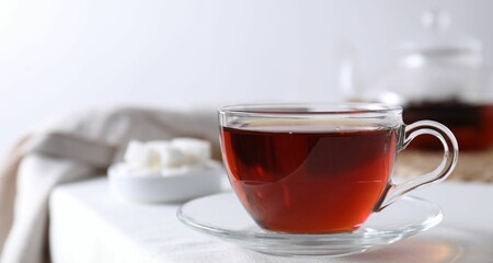 Refreshing black tea in cup on light table, closeup. Space for text