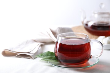 Refreshing black tea in cup on light table. Space for text