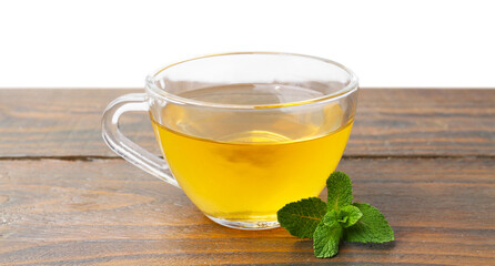 Aromatic mint tea in glass cup and fresh leaves on wooden table against white background