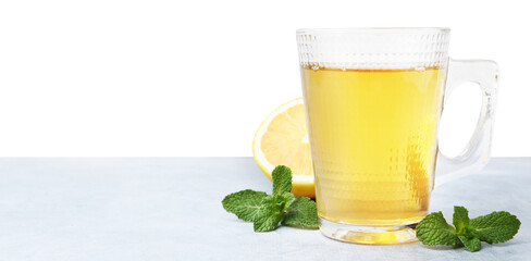 Aromatic mint tea in glass cup, fresh leaves and lemon on light gray table against white...