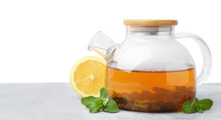 Aromatic mint tea in glass teapot, fresh leaves and lemon on light gray table against white...
