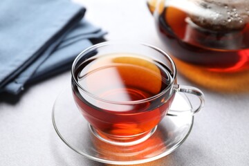 Aromatic black tea in cup and teapot on light table, closeup