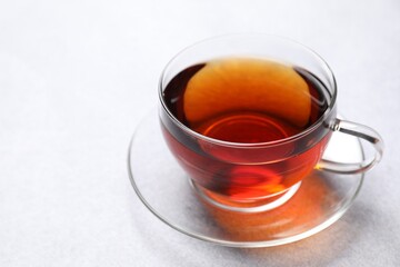 Aromatic black tea in cup on light table, closeup. Space for text