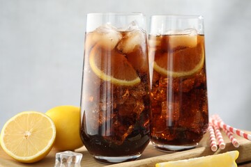 Refreshing iced cola with lemon slices on wooden table, closeup