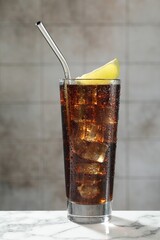 Refreshing iced cola with lime slice on white marble table