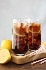 Refreshing iced cola with lemon slices on wooden table