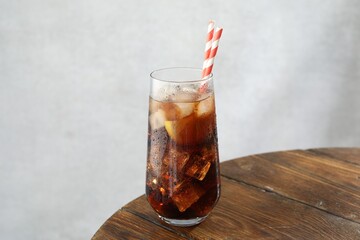 Refreshing iced cola with lemon slices on wooden table