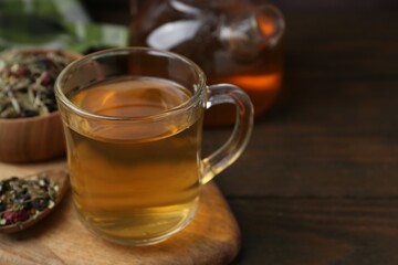 Delicious herbal tea and dry leaves on wooden table, closeup. Space for text