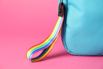 Backpack with keychain in LGBT colors on pink background, closeup. Space for text